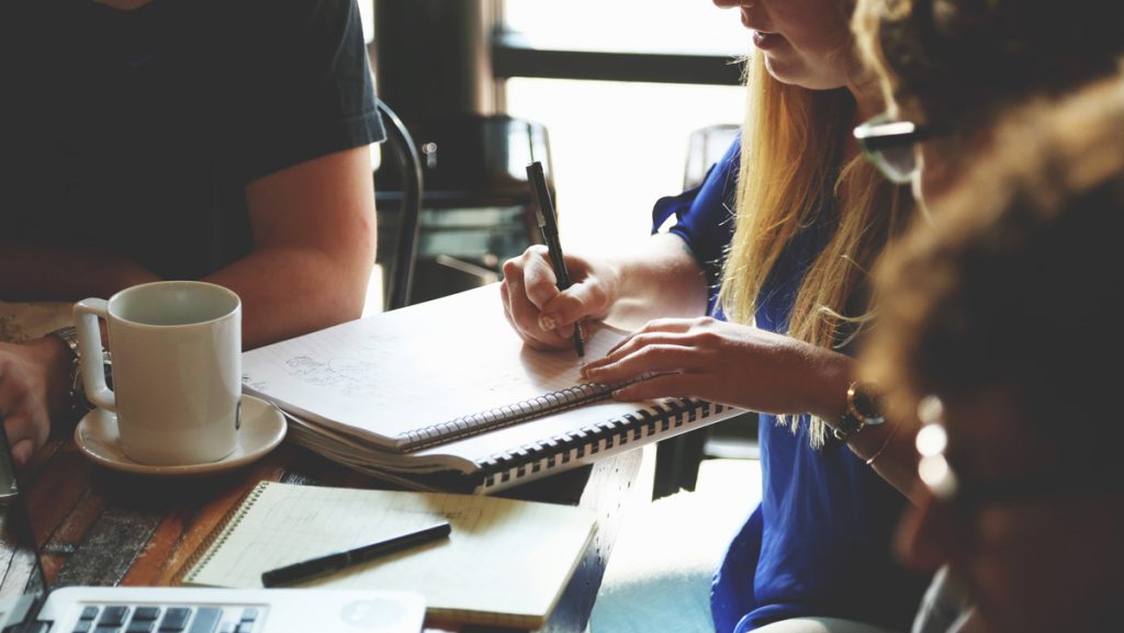 Situation einer Besprechung, eine Frau schreibt in einen Collegeblock