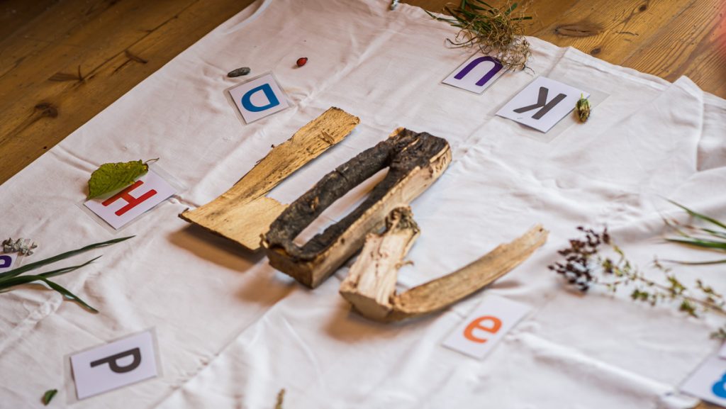 Buchstaben liegen auf einem Tuch, teilweise sind sie aus natürlichem Holz.